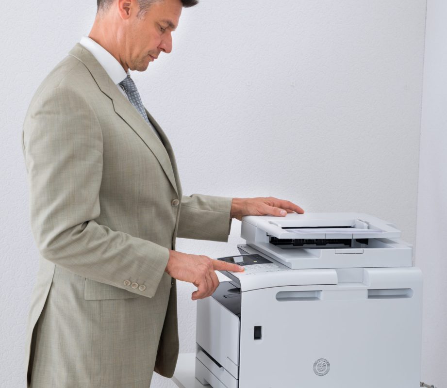 Side view of businessman keeping paper on photocopy machine in office